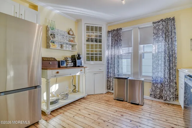 a kitchen with granite countertop a refrigerator a stove a dining table and chairs with wooden floor