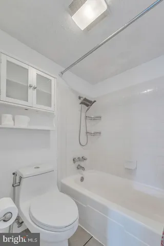 a white toilet sitting next to a bath tub and a shower