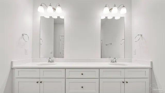 a bathroom with double vanity sinks a vanity a lamp and a mirror