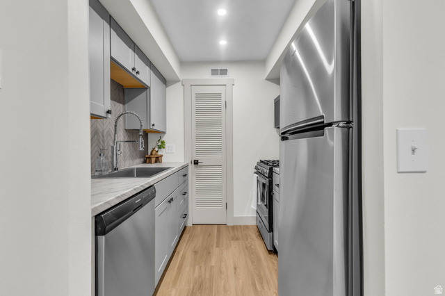 88 West 50 South, Unit C8 Centerville, UT 84014 - Photo 8 of 29 Galley kitchen featuring wood-finish flooring, light grey cabinetry with black hardware, and a stainless steel appliance suite