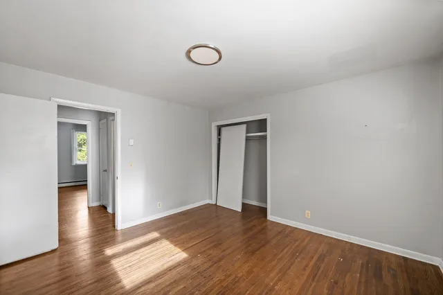 a view of an empty room with wooden floor and closet