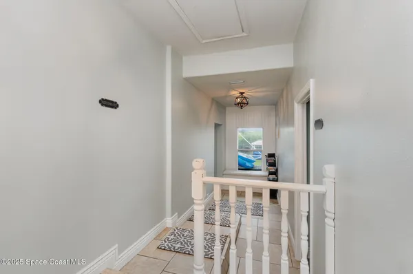 a view of a hallway to a livingroom with wooden floor and furniture