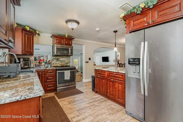 a kitchen with stainless steel appliances granite countertop a refrigerator a stove and a sink