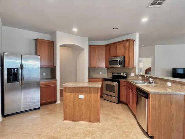 a kitchen with stainless steel appliances granite countertop a stove a sink and a refrigerator