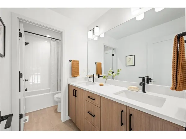 a bathroom with a double vanity sink a toilet a mirror and shower