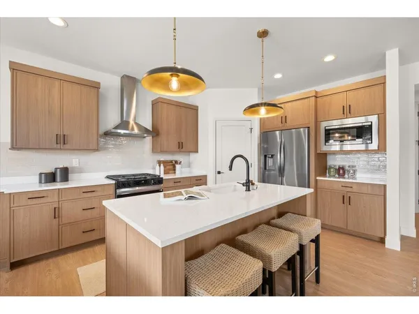 a kitchen with stainless steel appliances granite countertop a sink a stove a refrigerator cabinets and a dining table