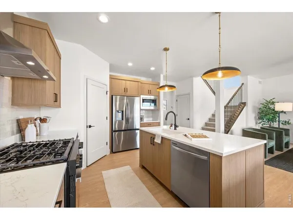 a kitchen with stainless steel appliances a sink a stove a refrigerator and island