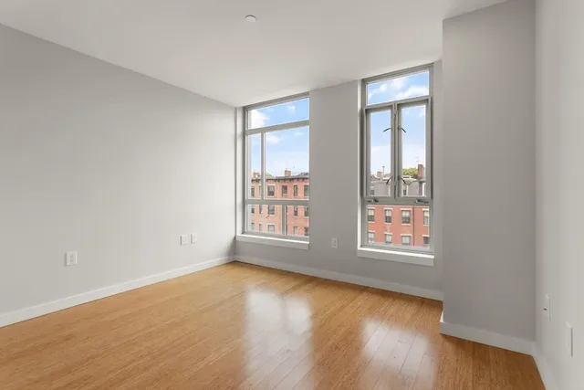 an empty room with wooden floor and windows