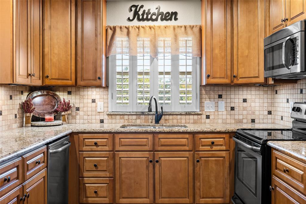 10517 Ravenswood Road Granbury, TX 76049 - Photo 13 of 35 a kitchen with stainless steel appliances granite countertop a sink a stove and cabinets