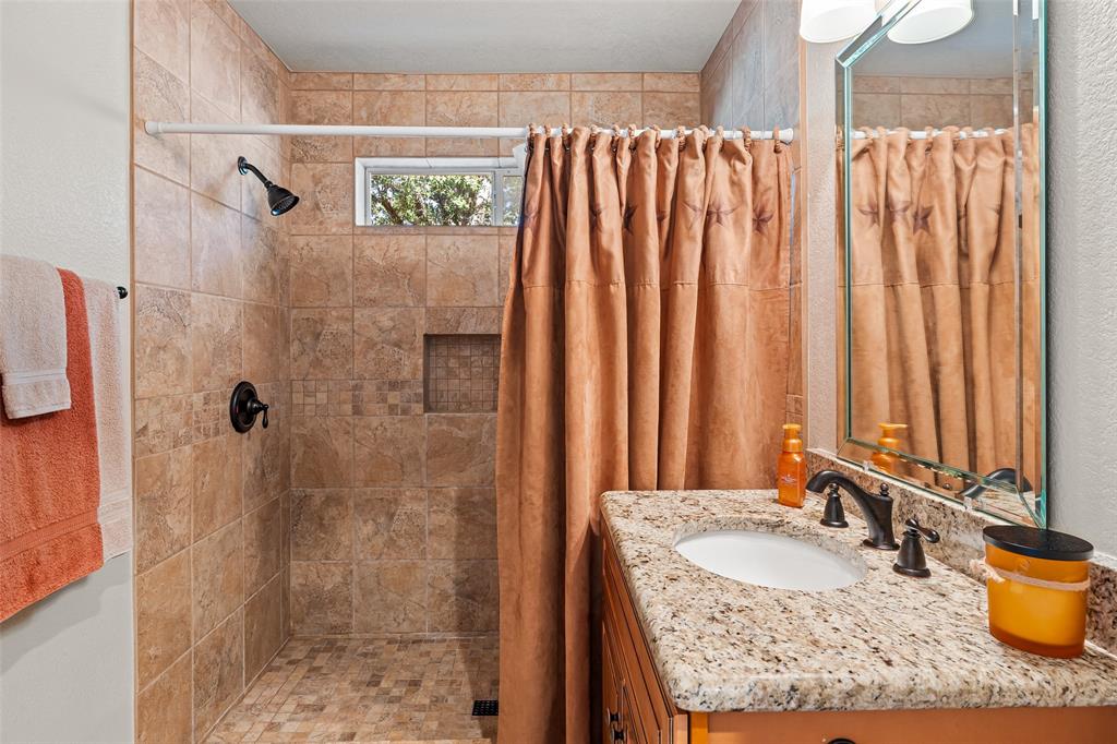 10517 Ravenswood Road Granbury, TX 76049 - Photo 16 of 35 a bathroom with a granite countertop sink and a mirror