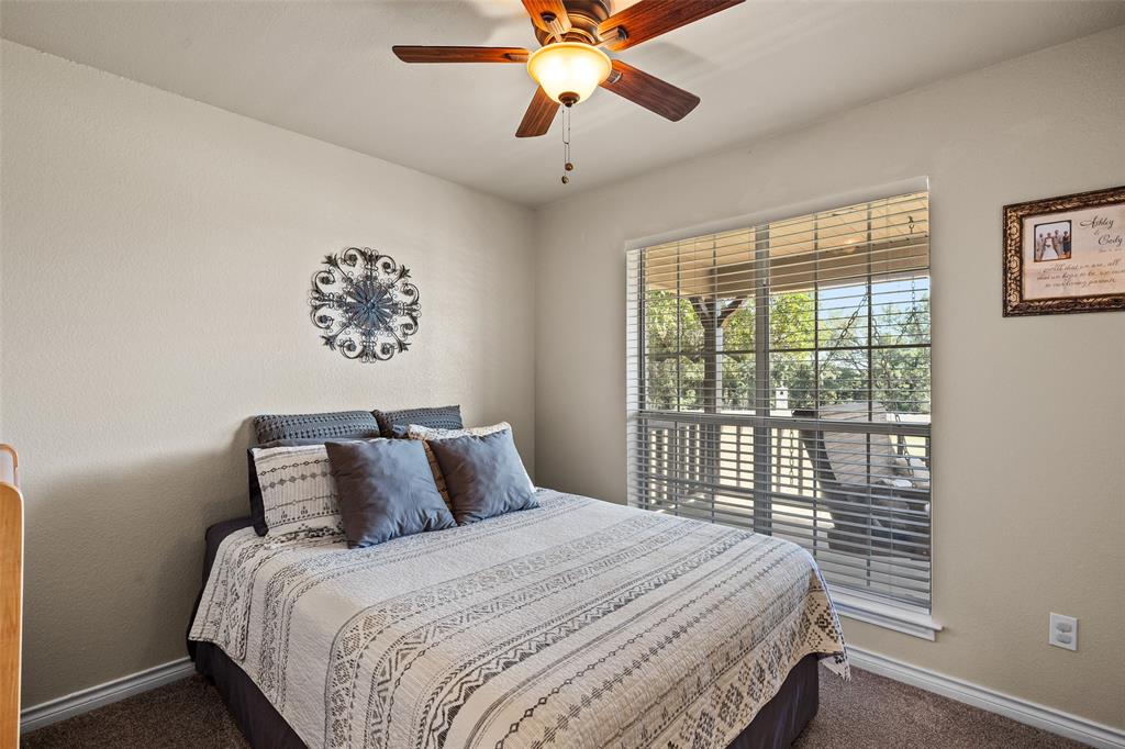 10517 Ravenswood Road Granbury, TX 76049 - Photo 17 of 35 a bedroom with a large bed and a chandelier