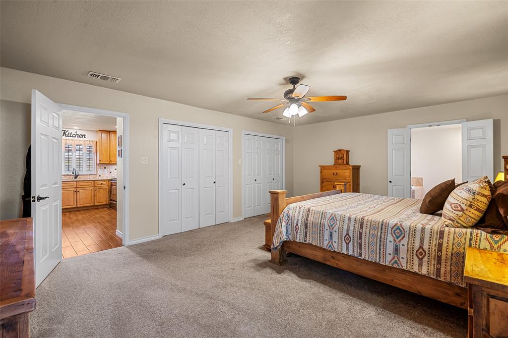 10517 Ravenswood Road Granbury, TX 76049 - Photo 19 of 35 a spacious bedroom with a bed and wooden floor