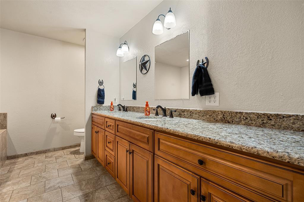 10517 Ravenswood Road Granbury, TX 76049 - Photo 21 of 35 a spacious bathroom with a granite countertop sink a mirror and a