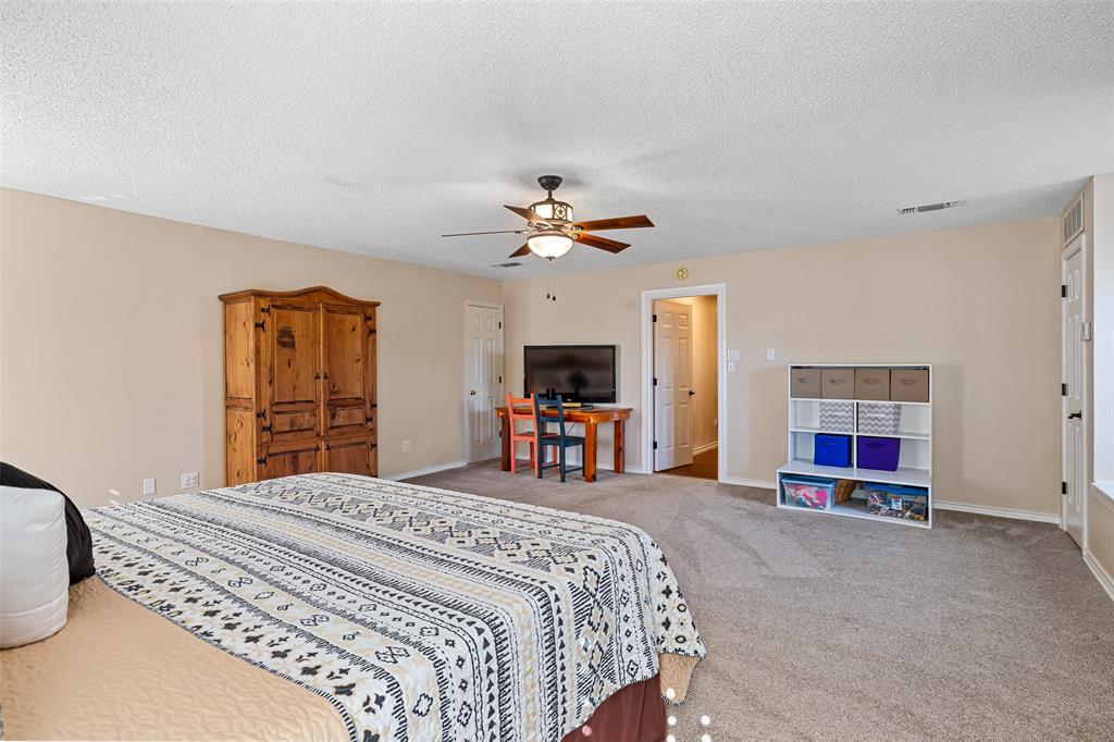 10517 Ravenswood Road Granbury, TX 76049 - Photo 23 of 35 a bedroom with a large bed and a chandelier