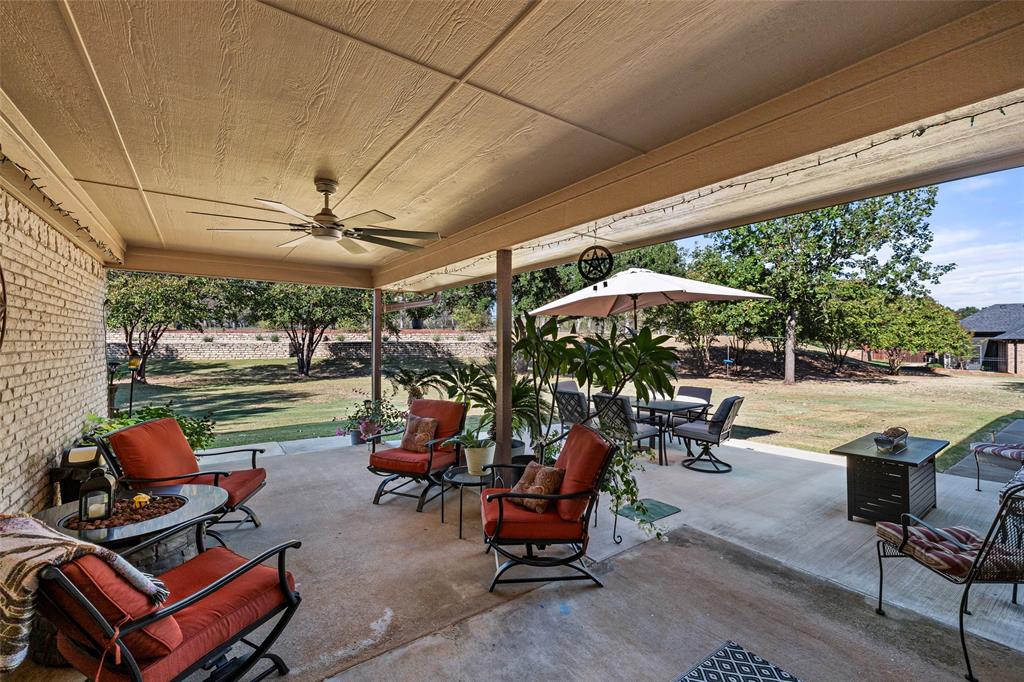 10517 Ravenswood Road Granbury, TX 76049 - Photo 27 of 35 a view of a patio with table and chairs under an umbrella