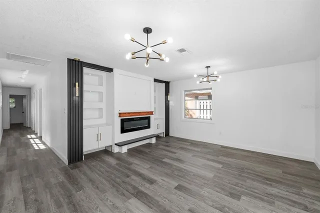 a view of an empty room with wooden floor and a ceiling fan