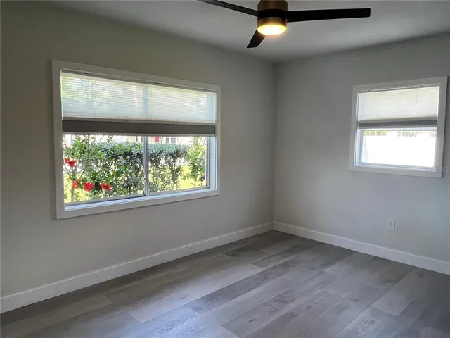 a view of empty room with wooden floor and fan