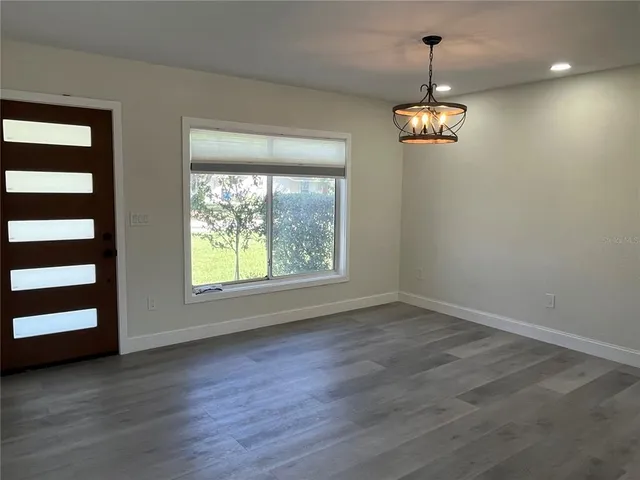 a view of wooden floor chandelier and windows in a room