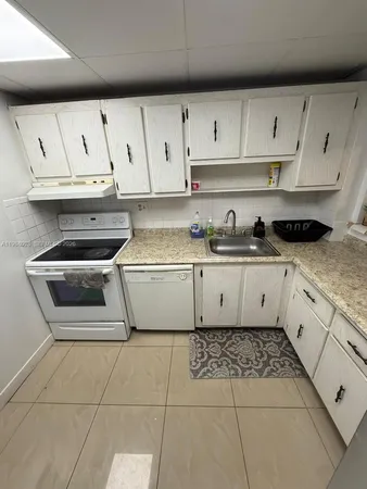 a kitchen with white cabinets a sink and appliances
