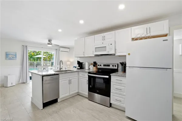 a kitchen with granite countertop white cabinets and white appliances