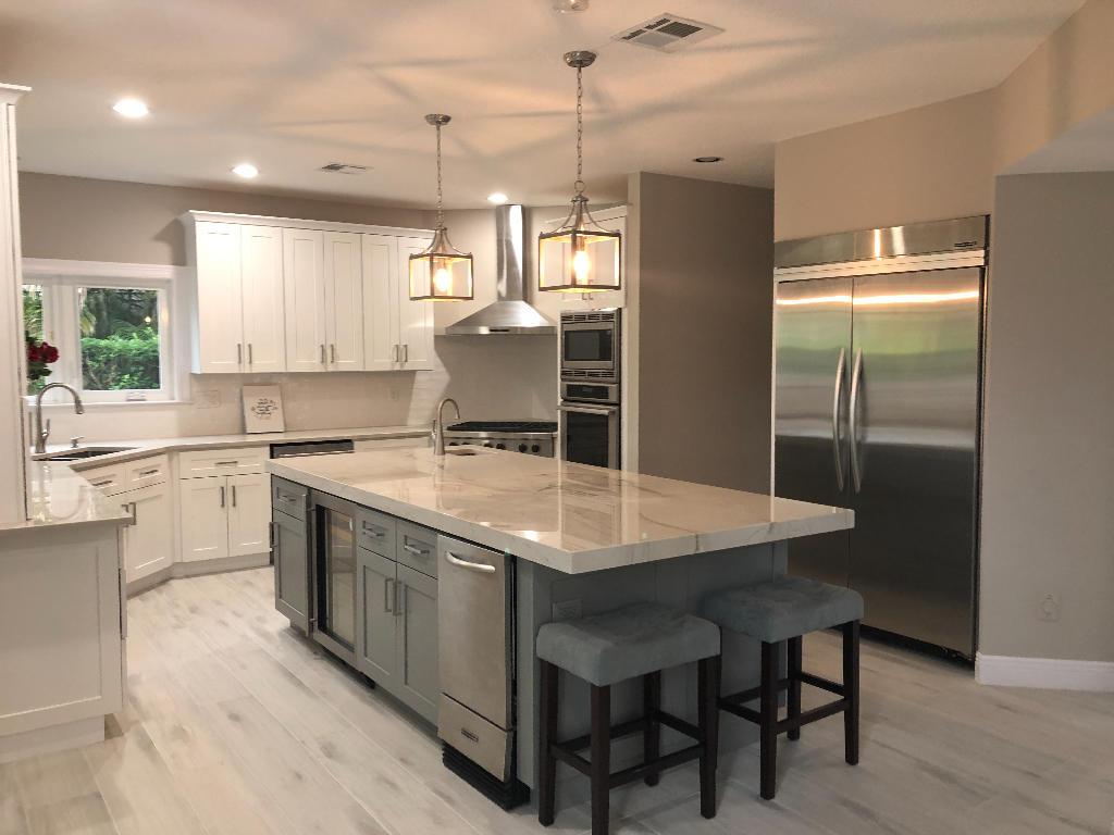18169 Southeast Ridgeview Drive Tequesta, FL 33469 - Photo 9 of 23 a kitchen with kitchen island a counter top space a sink refrigerator and cabinets