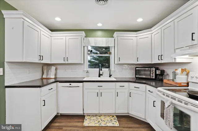 a kitchen with white cabinets white stainless steel appliances and sink