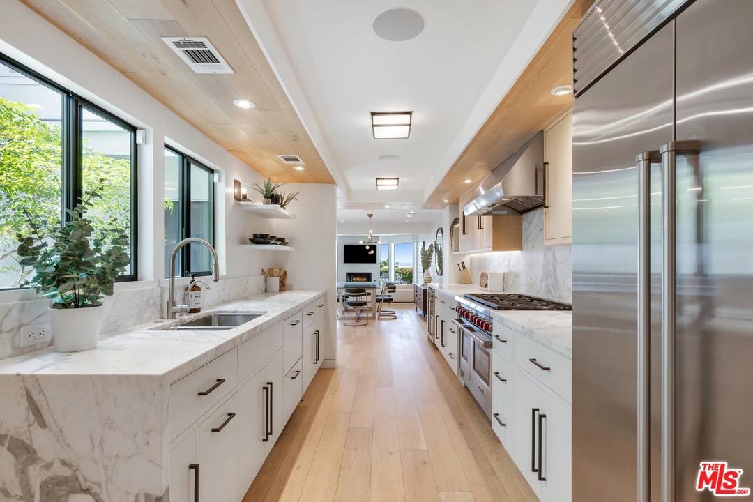 a large kitchen with stainless steel appliances a sink stove and cabinets