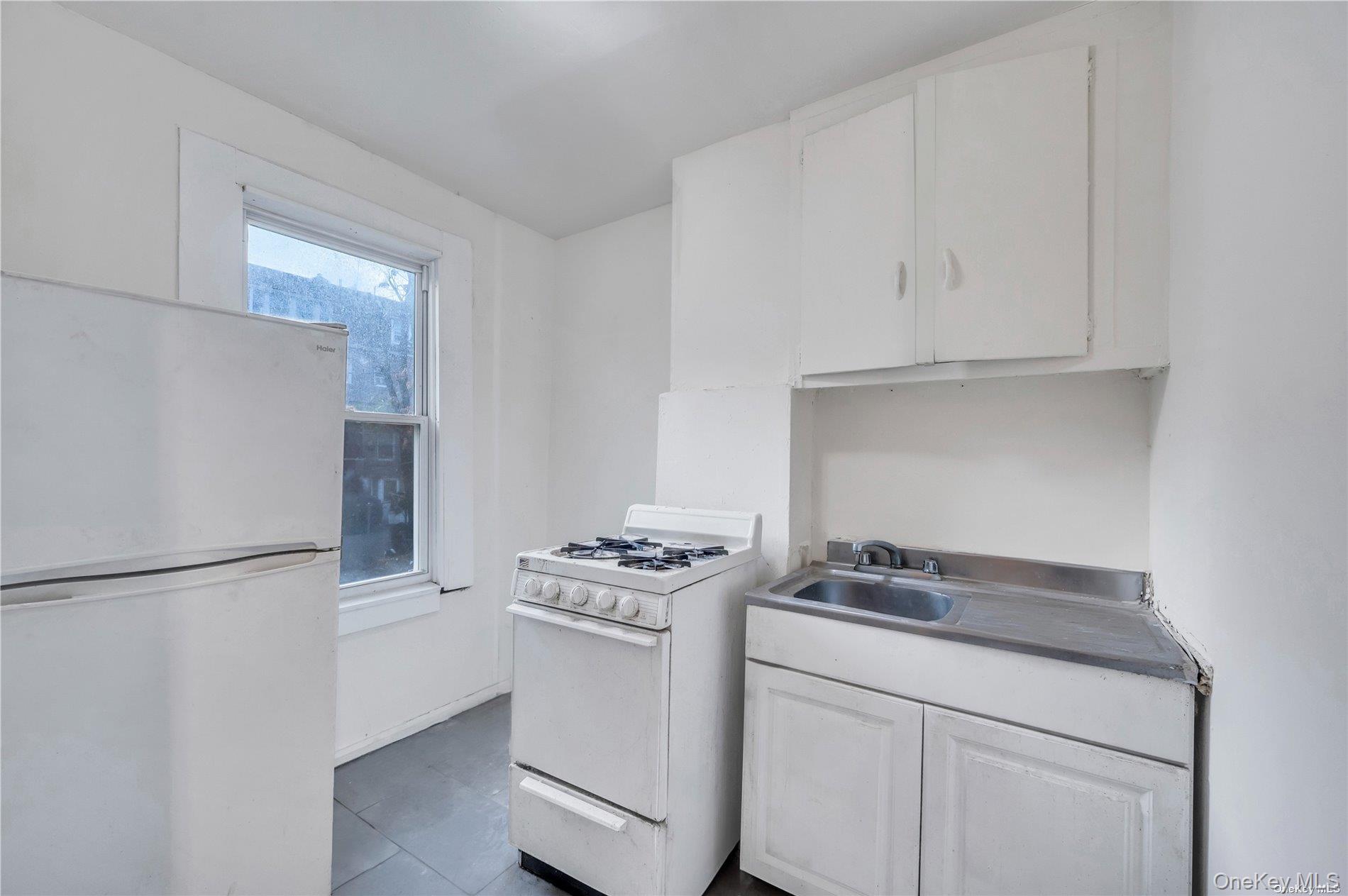 37-58 79th Street Queens, NY 11372 - Photo 20 of 28 a kitchen with white cabinets and white appliances