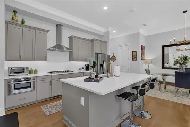 a kitchen with a stove a sink a kitchen island with chairs and wooden floor