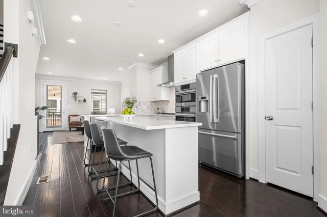 a kitchen with stainless steel appliances a refrigerator a stove a sink dishwasher with a dining table and chairs