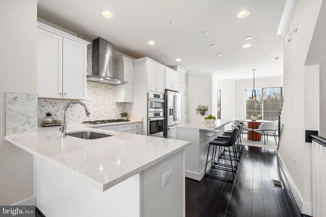 a kitchen with a sink a stove and chairs with wooden floor