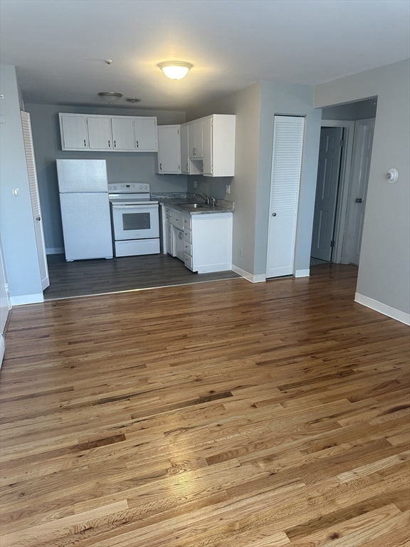 39 Carey Avenue, Unit 5 Watertown, MA 02472 - Photo 4 of 12 a view of kitchen and empty room with wooden floor