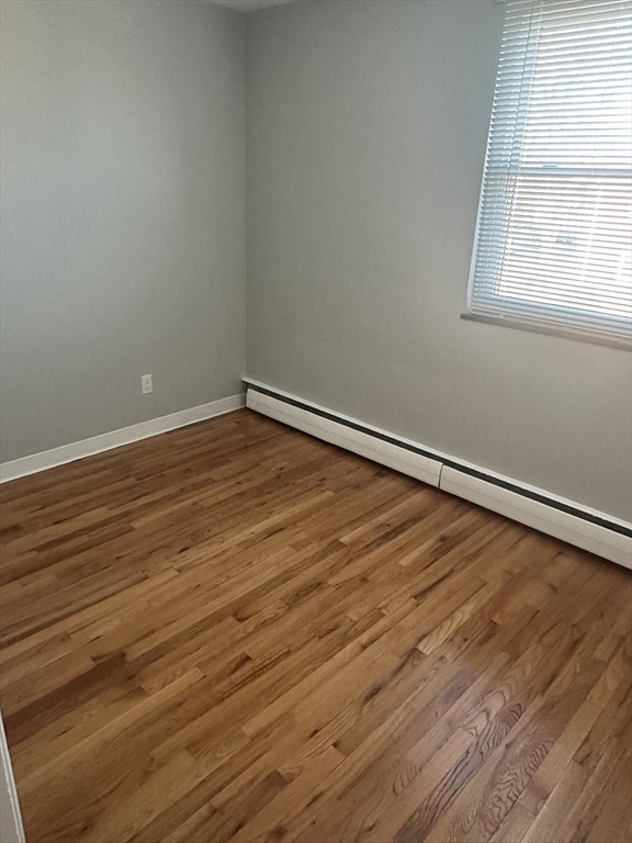 39 Carey Avenue, Unit 5 Watertown, MA 02472 - Photo 6 of 12 an empty room with wooden floor and windows