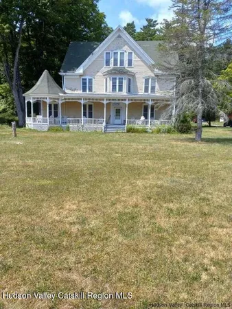 a view of a big house with a big yard and large trees