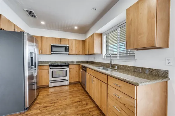 a kitchen with granite countertop a sink stainless steel appliances and cabinets