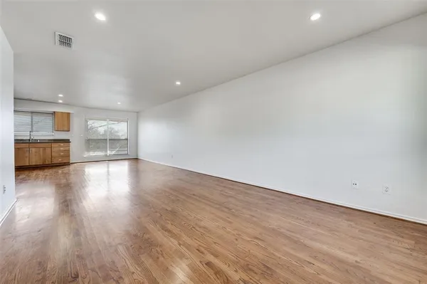 wooden floor in an empty room with a kitchen