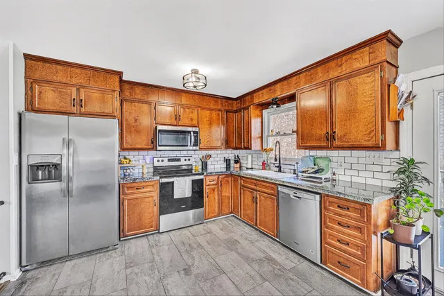 a kitchen with stainless steel appliances granite countertop a stove top oven a refrigerator and a sink with granite countertops