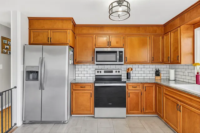a kitchen with stainless steel appliances granite countertop a refrigerator a stove top oven a sink and dishwasher