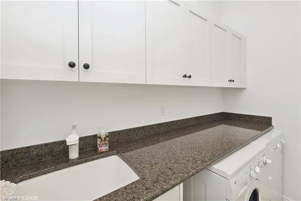 a kitchen with granite countertop white cabinets and a sink