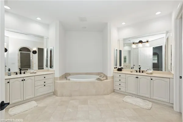 a spacious bathroom with a double vanity sink mirror and bathtub