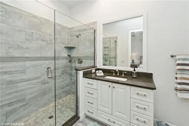 a bathroom with a granite countertop sink a mirror and a shower