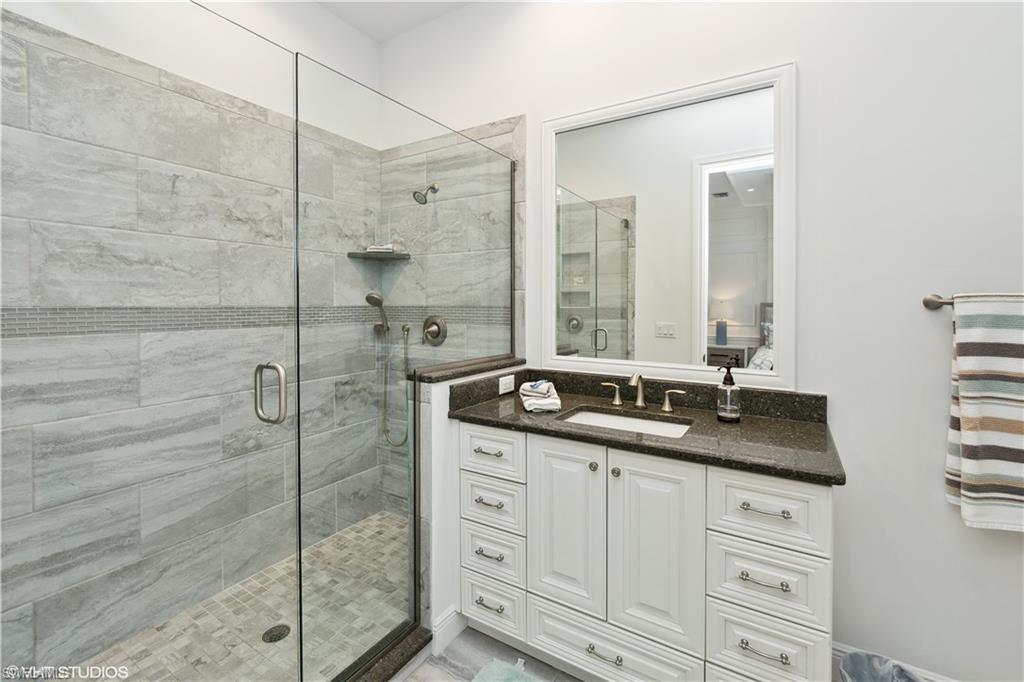 6501 Crown Colony Place, Unit 4201 Naples, FL 34108 - Photo 29 of 35 a bathroom with a granite countertop sink a mirror and a shower