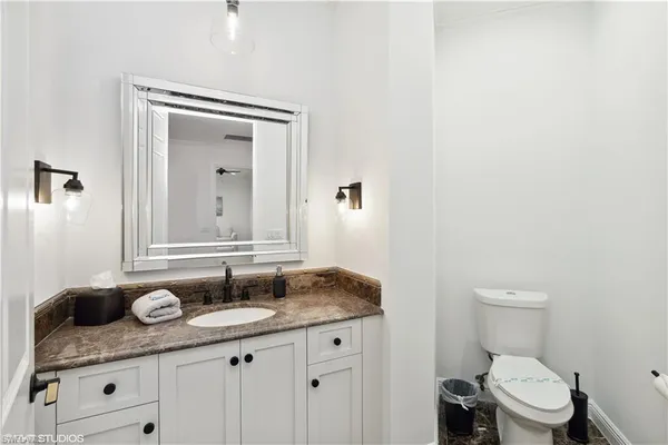 a bathroom with a granite countertop sink a toilet and a mirror