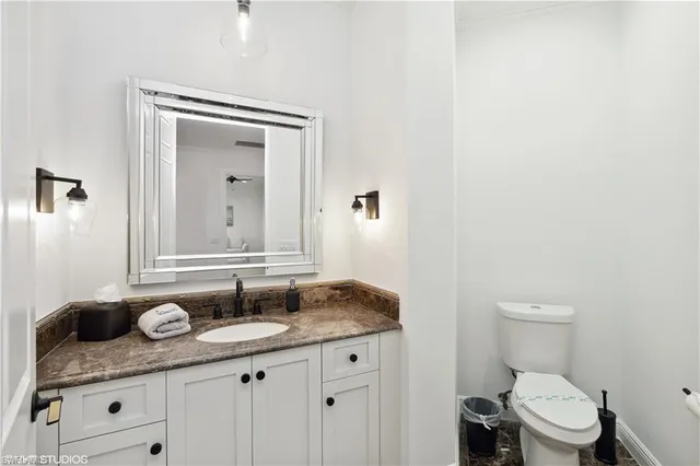 a bathroom with a granite countertop sink a toilet and a mirror
