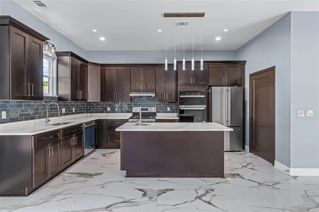 a kitchen with kitchen island a counter top space cabinets and stainless steel appliances