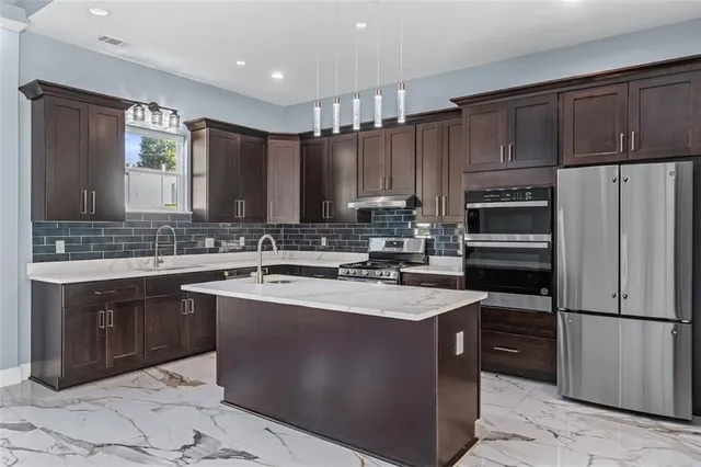a kitchen with kitchen island granite countertop a sink stove and refrigerator