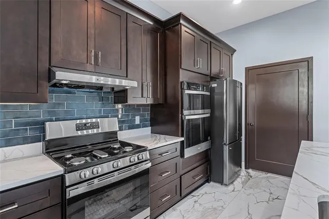 a kitchen with stainless steel appliances granite countertop a stove refrigerator and cabinets
