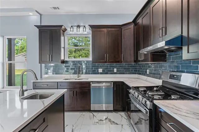 a kitchen with stainless steel appliances granite countertop a sink stove and refrigerator