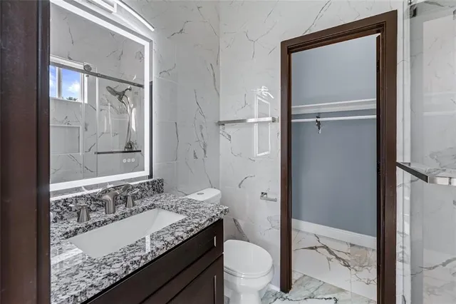 a bathroom with a granite countertop sink toilet and shower