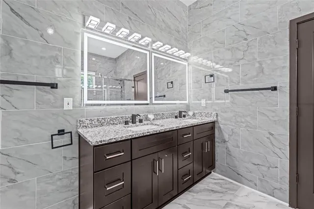a bathroom with a granite countertop sink a large mirror and a shower